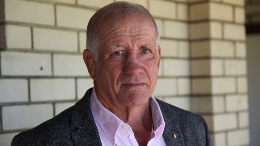 Head and chest shot of former ARU Board member Geoff Stooke standing in front of a cream bricked building