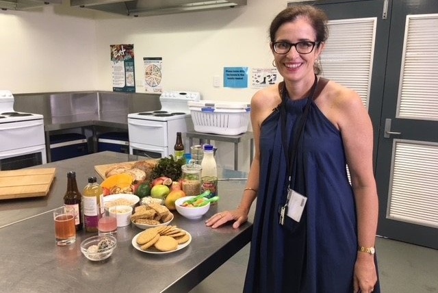 QUT Faculty of Health nutritionist Dr Helen Vidgen stands in a kitchen with food on a counter.