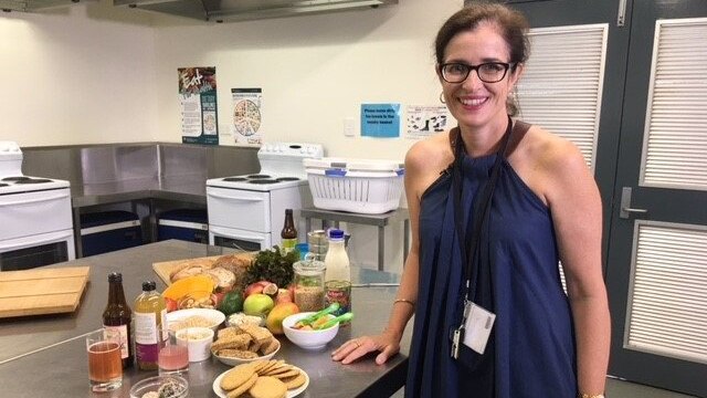 QUT Faculty of Health nutritionist Dr Helen Vidgen stands in a kitchen with food on a counter.