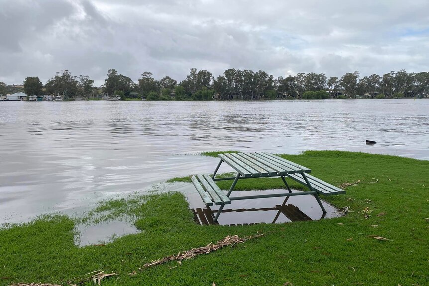 A park bench on the edge of a vast flooded area.