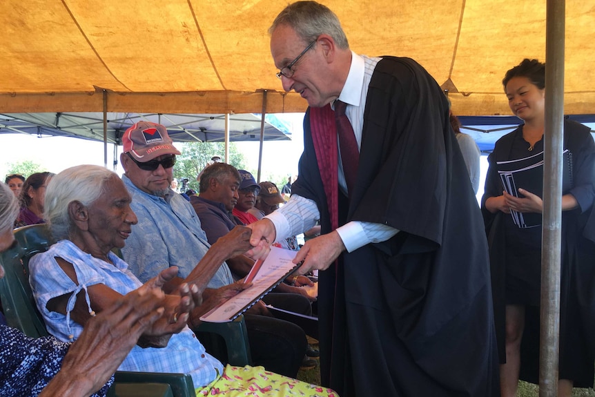 Federal Court Justice Anthony North hands the official determinations to traditional owner Rita Augustine.