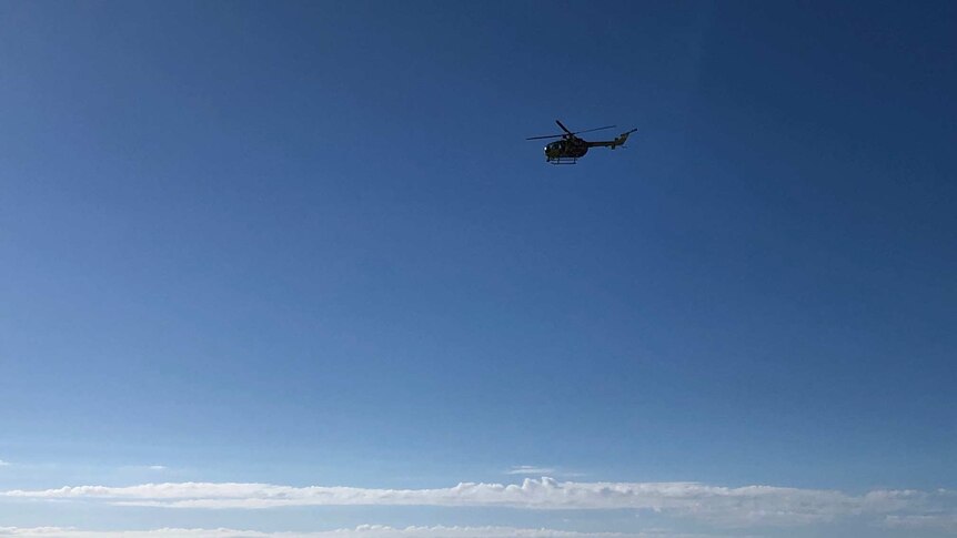 A helicopter flies above Twin Waters beach.