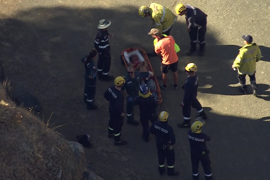 A teenager in a rescue bed, surrounded by emergency services. 
