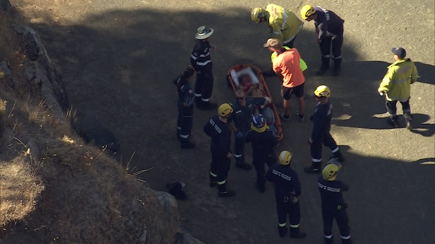 A teenager in a rescue bed, surrounded by emergency services. 