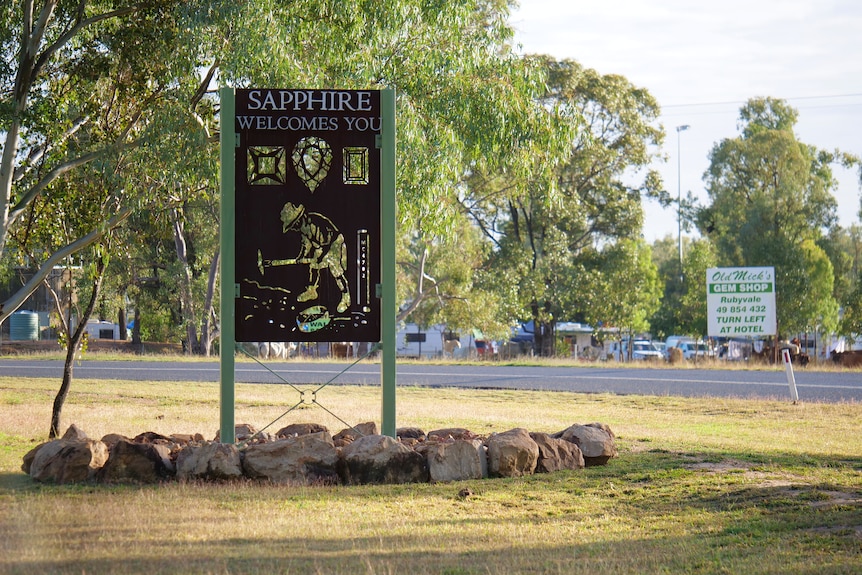 A sign that says 'Sapphire welcomes you', grass and road in the background.