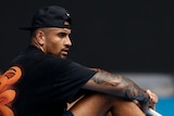 Australian tennis player Nick Kyrgios sits on the blue court during a practise session before the 2023 Australian Open.
