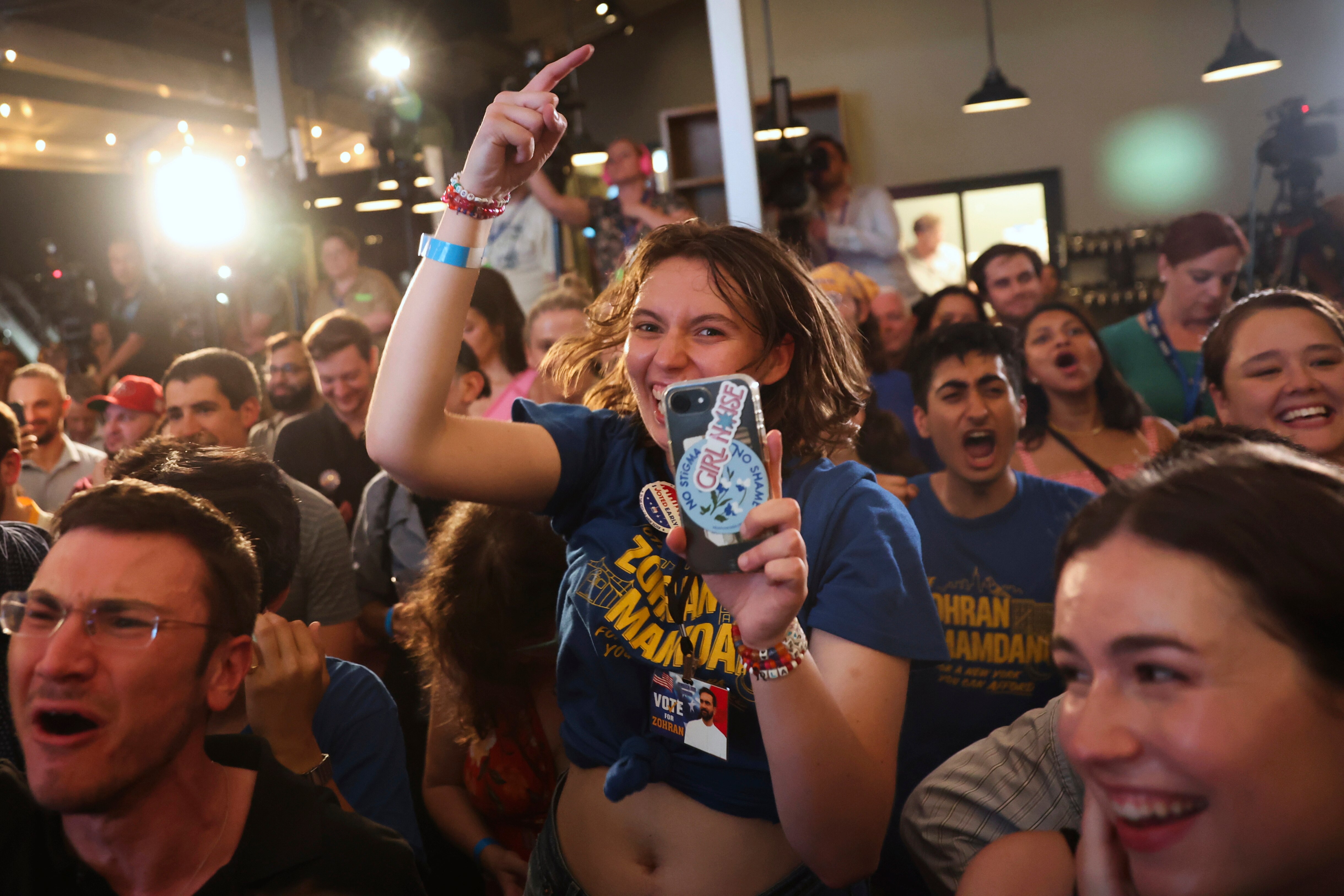 A person cheers with one hand up in a crowd 