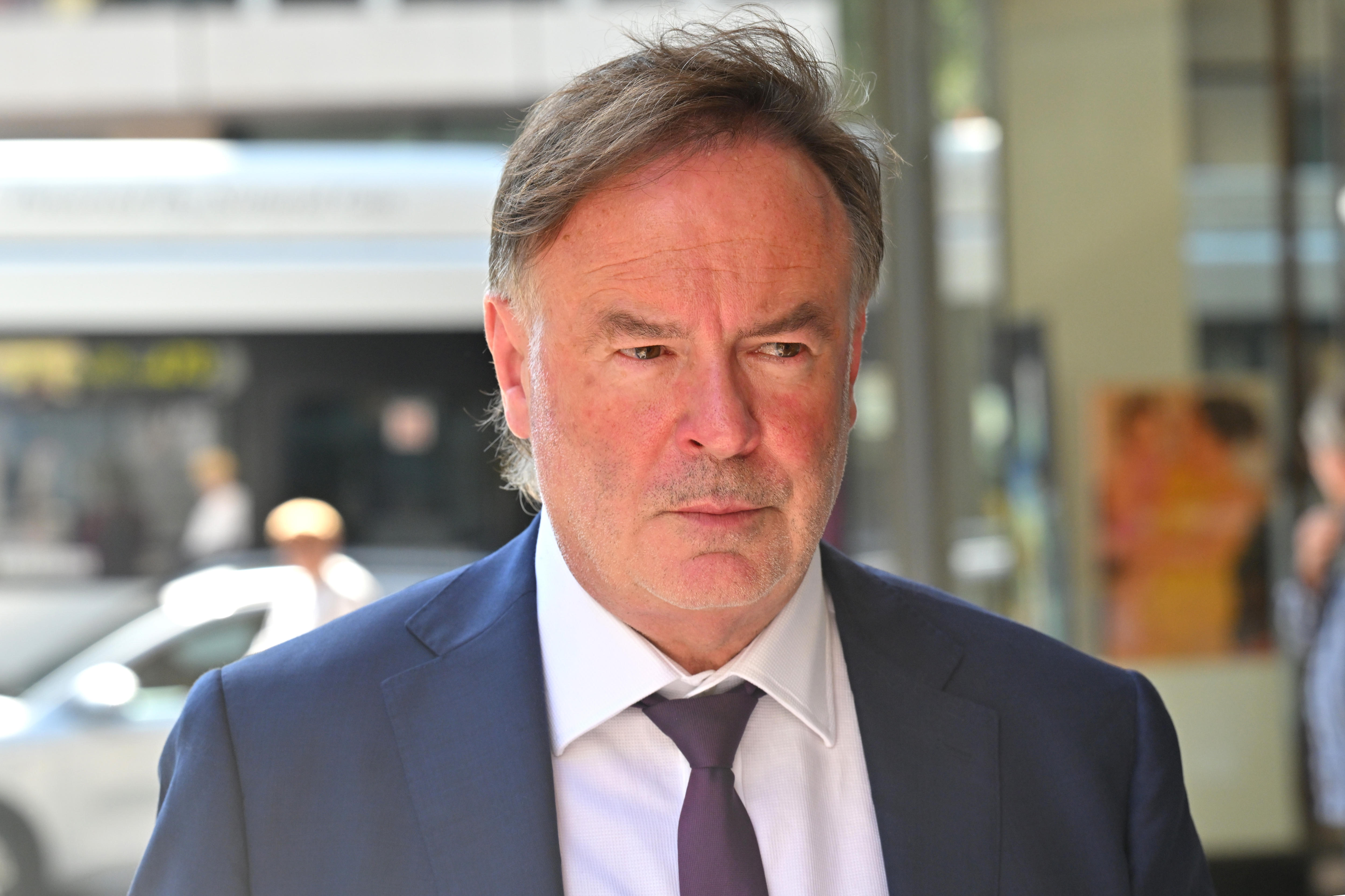 Gregory Geason wearing a blue suit with bus in background