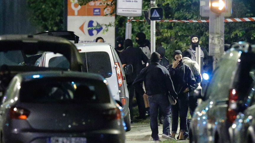 Cars and French police stand in a crowd, preparing to to take place in a raid near Notre Dame cathedral.