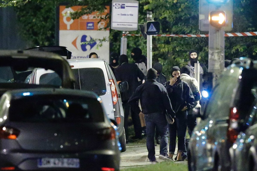 Cars and French police stand in a crowd, preparing to to take place in a raid near Notre Dame cathedral.