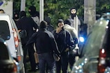 Cars and French police stand in a crowd, preparing to to take place in a raid near Notre Dame cathedral.