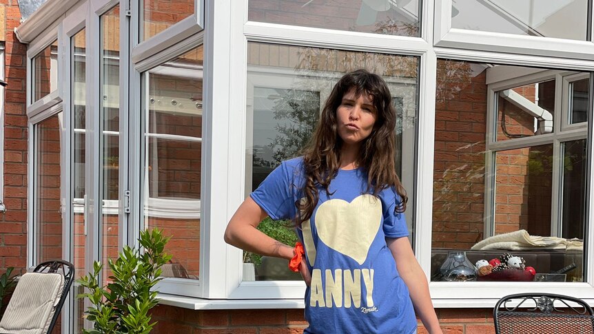 Singer Fanny Lumsden poses with a watering can outside a greenhouse while on tour in the UK. 