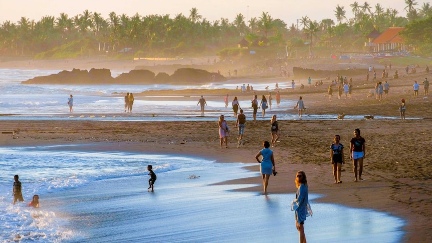 Orang-orang di pantai di Bali saat matahari terbenam