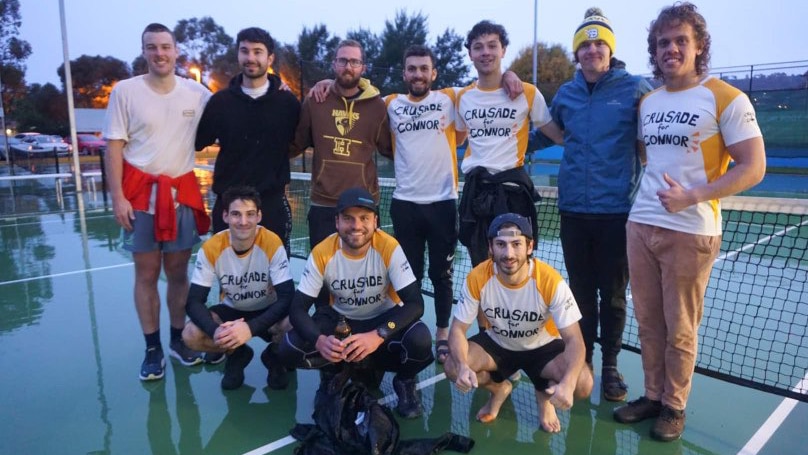 10 young men gather around a wet tennis court 