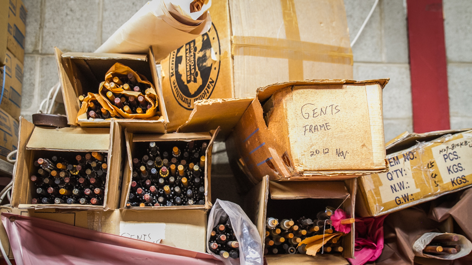 Boxes of umbrella frames are stacked in piles within the workshop.