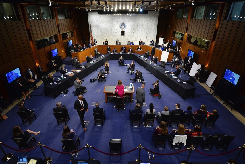A photo taken from on high showing the layout of the hearing room. It is spacious, Coney Barrett is in the centre.