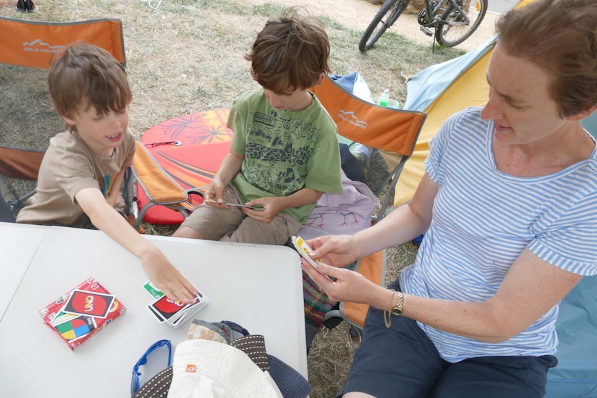 Anna Genat plays Uno on a camping table with her two sons.