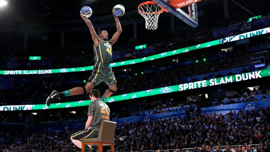 Jeremy Evans leaps over a man sitting in a chair as he competes in the slam dunk contest.