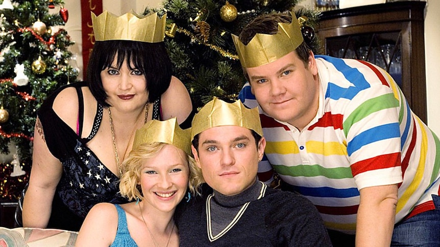 Four friends pose in front of Christmas trees,