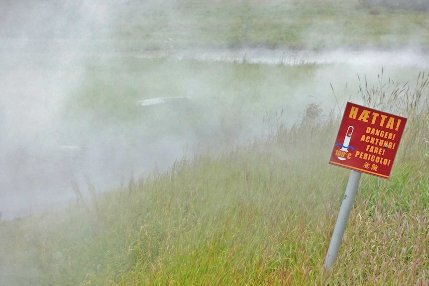 warning sign in Iceland where steam rises in a geothermal area