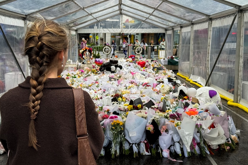 A woman pays tribute at the floral memorial for the victims of the Westfield Bondi Junction stabbing attack