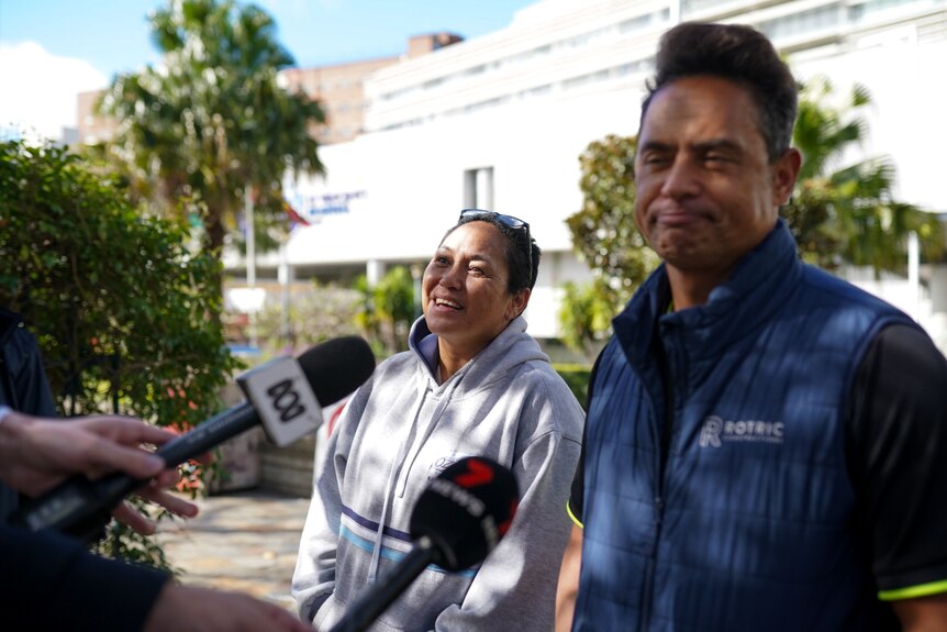 A man and a woman speak to the media outside a hospital.