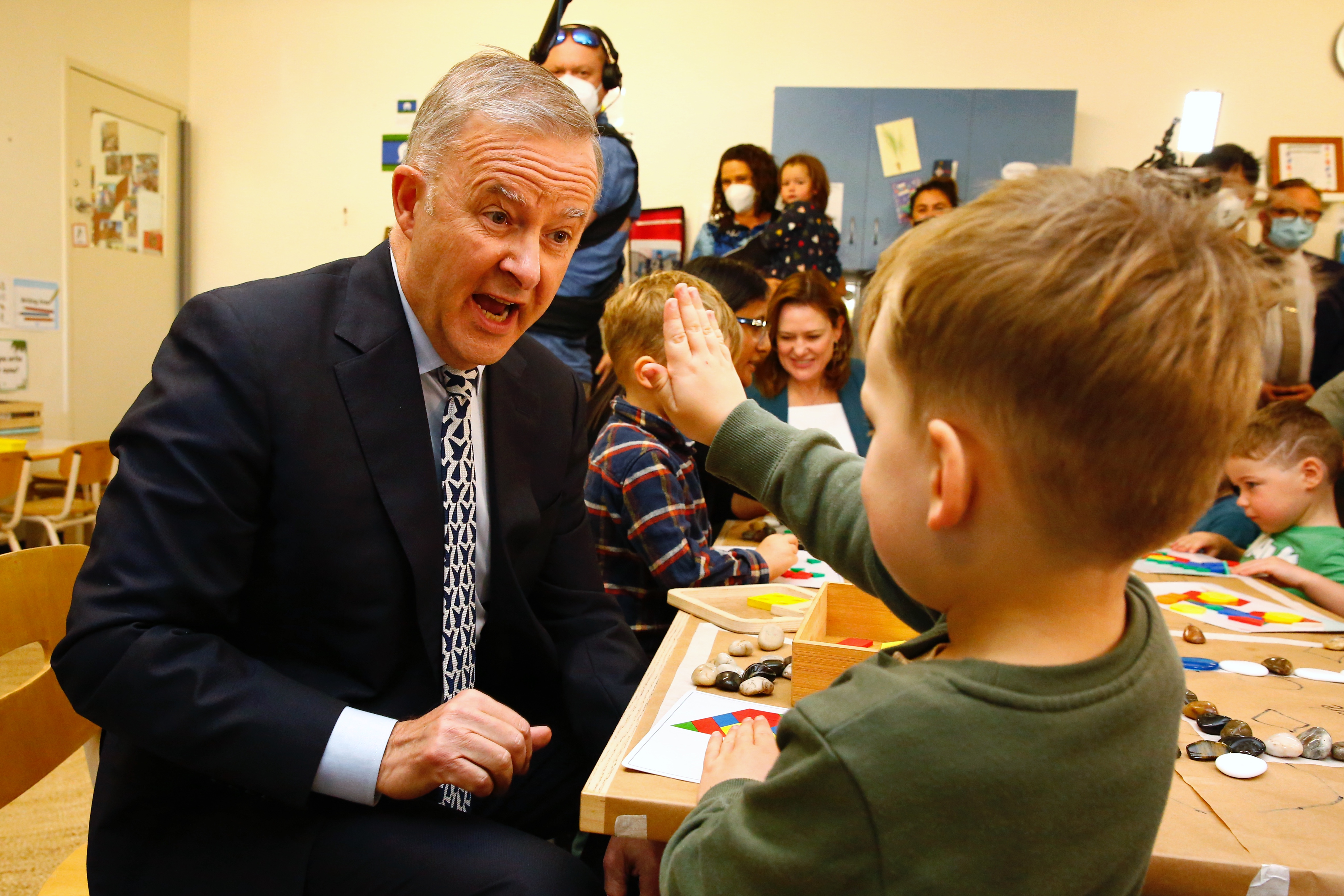 A boy goes to give an excited Albanese a high five in a classroom