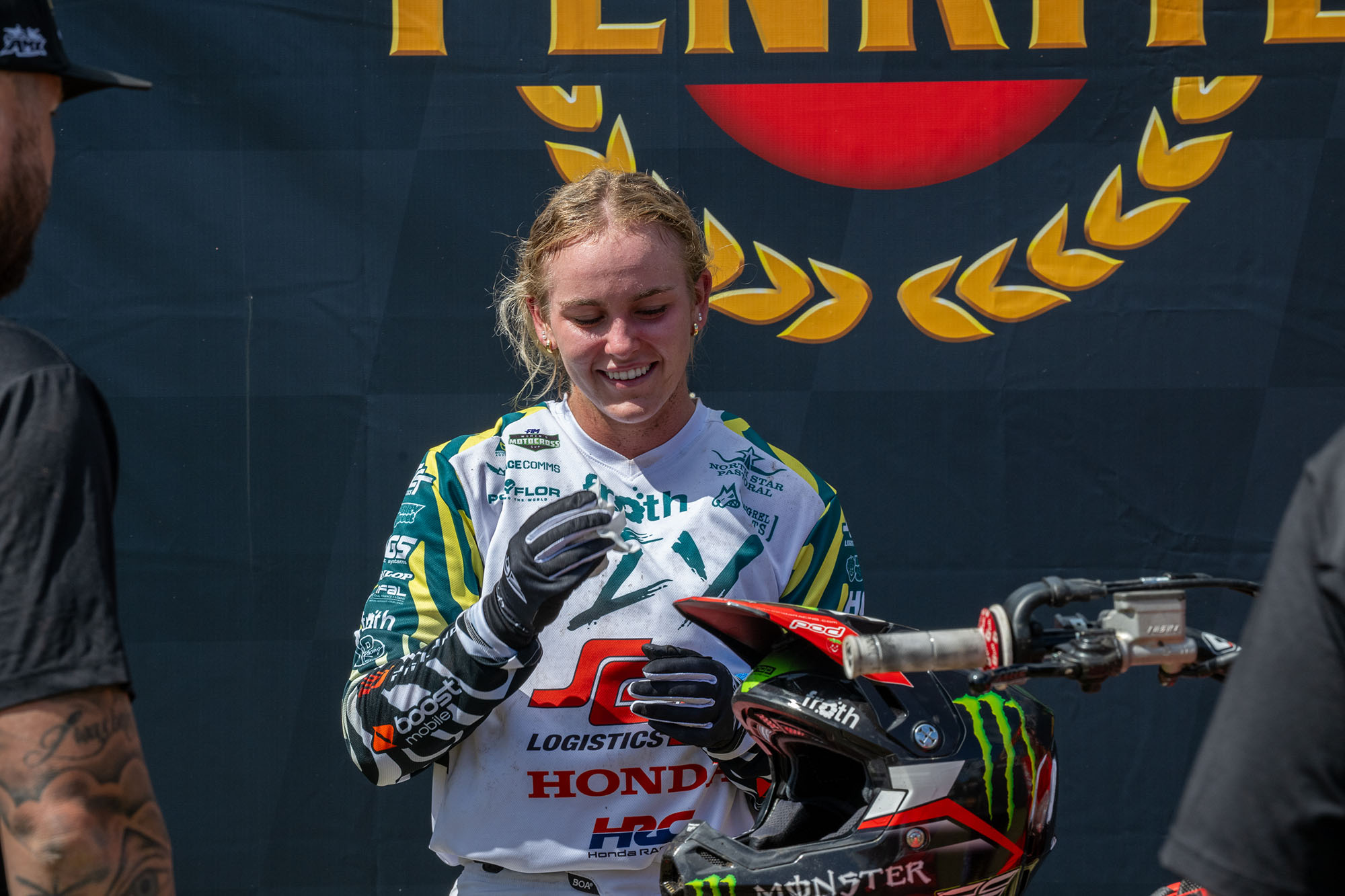 Uma jovem mulher andando de motocross em pé sem capacete depois de uma corrida