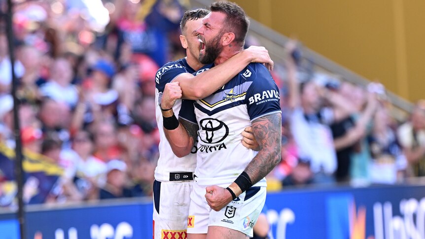 Two Cowboys players embrace as they celebrate an NRL try against the Dolphins.