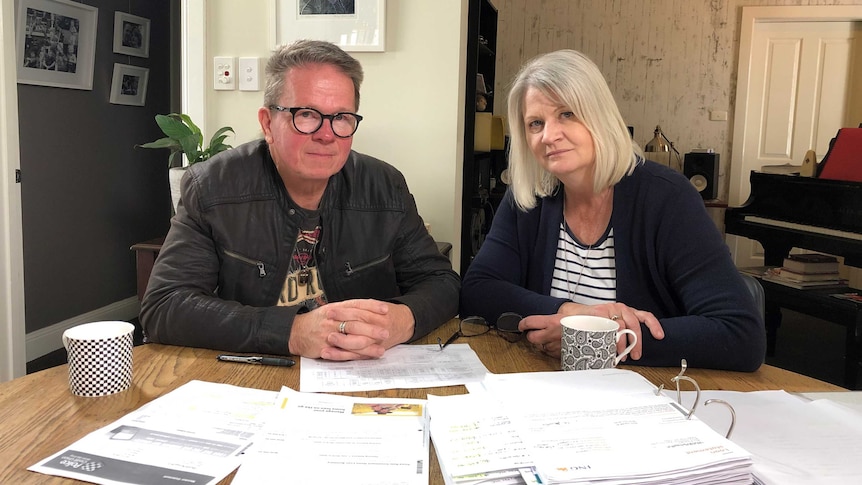 Peter and Bronwyn Dwight sitting at a table covered in folders and financial documents