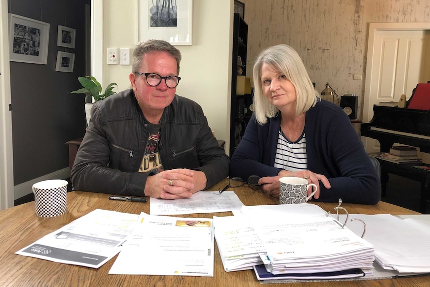 Peter and Bronwyn Dwight sitting at a table covered in folders and financial documents