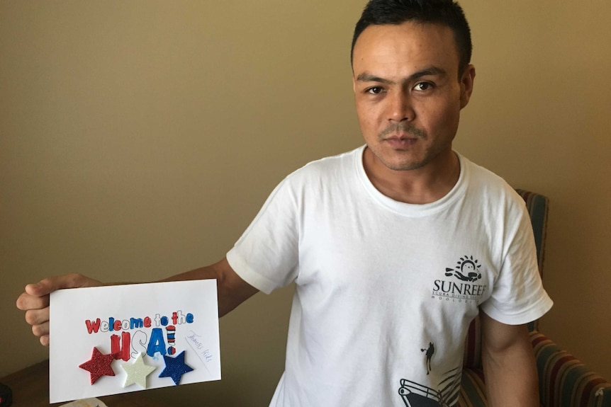 A man hold up a card that says Welcome to the USA.