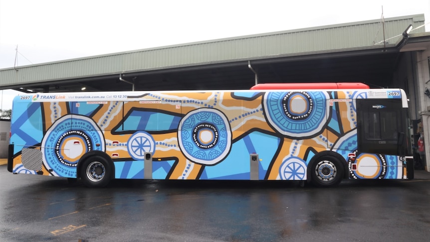 A bus covered in a bright blue and yellow Indigenous design.