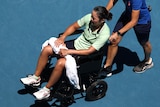 Harmony Tan is escorted from Margaret Court Arena in a wheelchair