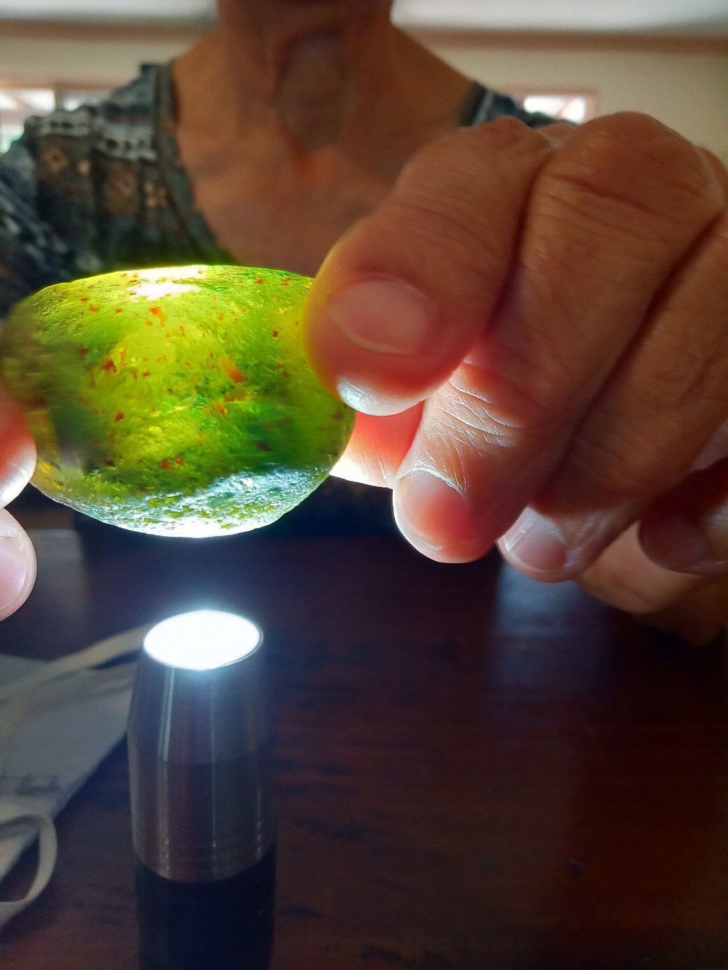 A close-up of hands holding a large green and yellow rock