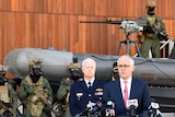 Heavily armed soldiers and a sniper rifle are seen behind Prime Minister Malcolm Turnbull as he speaks to the media.