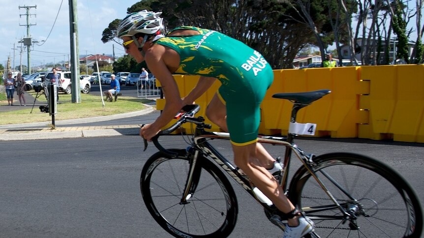 A man in a green lycra suit on a racing bicycle.
