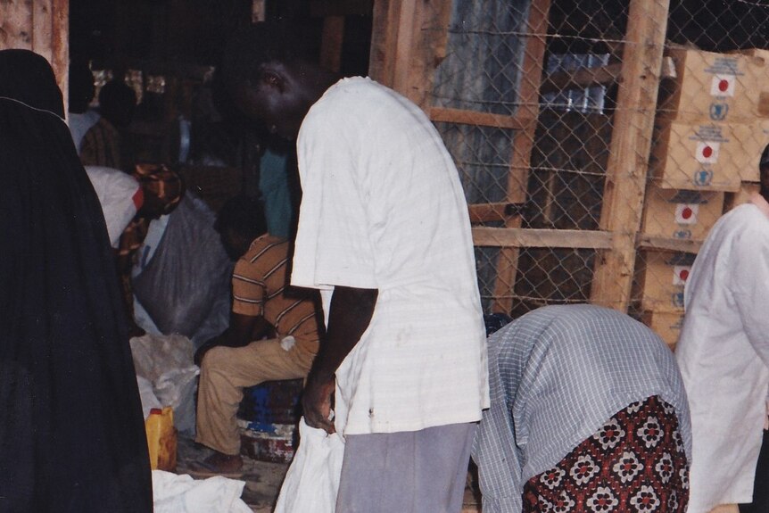 People holding sacks wait to collect food rations