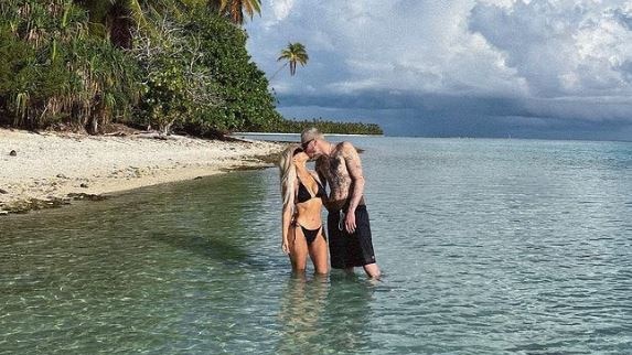 A woman and man kiss on an island