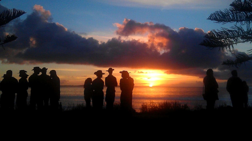 The sun rises over an Anzac Day dawn service.