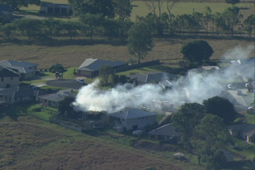 An aerial image of smoke billowing into the sky from a suburban street.