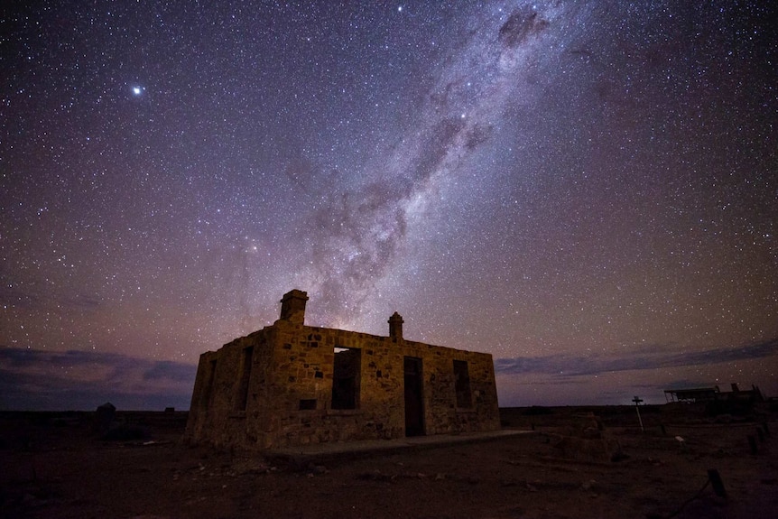 A roofless, abandoned building under the Milky Way