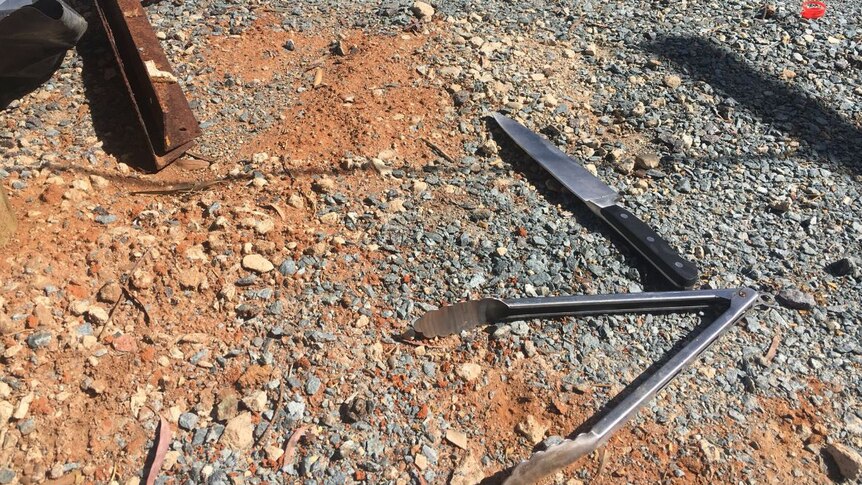 Tools, including a knife and tongs, lie on the ground at the scene of a pop-up kitchen explosion in Fyshwick.