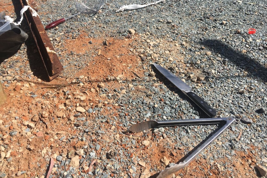 Tools, including a knife and tongs, lie on the ground at the scene of a pop-up kitchen explosion in Fyshwick.