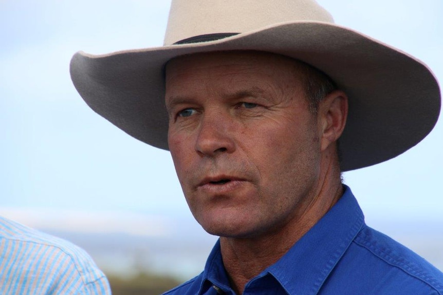 John Hammond wears a blue shirt and brown hat