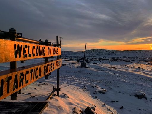 Sunrise over Antarctic station with sign saying 'welcome to Davis Antarctica'