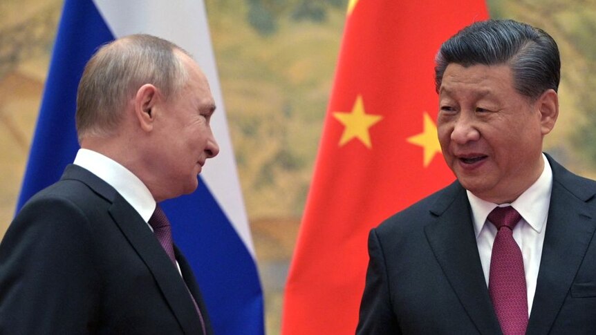 Russia's president vladimir putin and china's president xi jinping facing one another in front of russian and PRC flag.