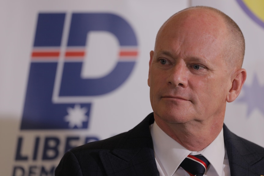 Campbell Newman standing in front of a Liberal Democrats logo. 