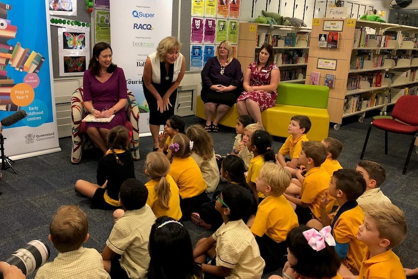Premier Annastacia Palaszczuk and teachers in front of primary school children in a school library.