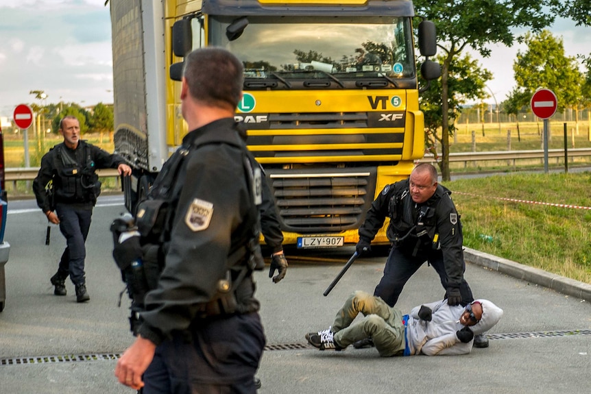 French gendarmes attempt to block a migrant after he entered the Eurotunnel site near Calais